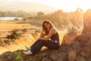 A tranquil sunset portrait session among tall grass with mountains in the background.