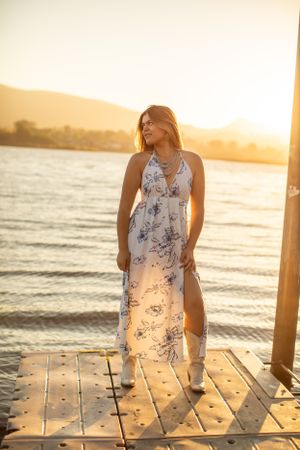 A sunset dock portrait featuring a floral maxi dress and warm evening light over water.