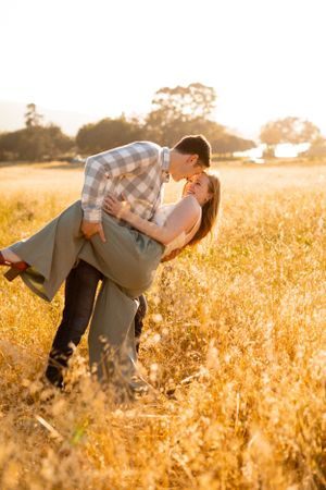 Romantic couple sharing a playful dip pose in a golden sunset field.