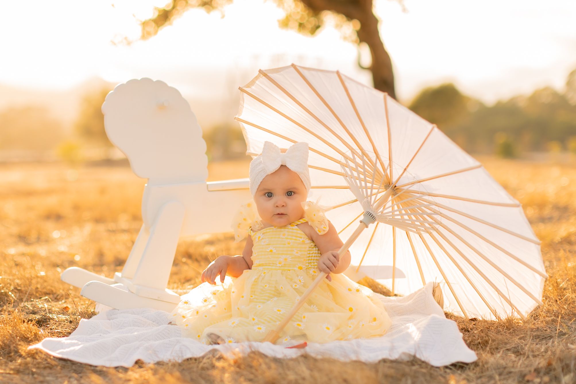 A series of dreamy outdoor photos featuring white parasols and flowy dresses at golden hour in a sunlit field.