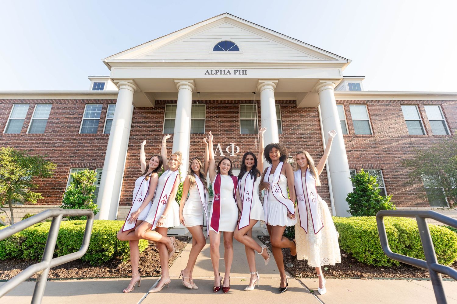 Seven Alpha Phi sorority graduates celebrate in front of their chapter house on campus.