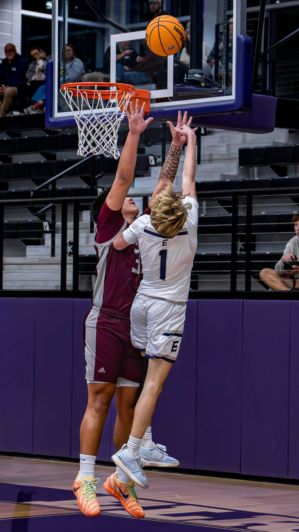 Elkins AR basketball players attempts a layup under the hoop during an intense game sequence.