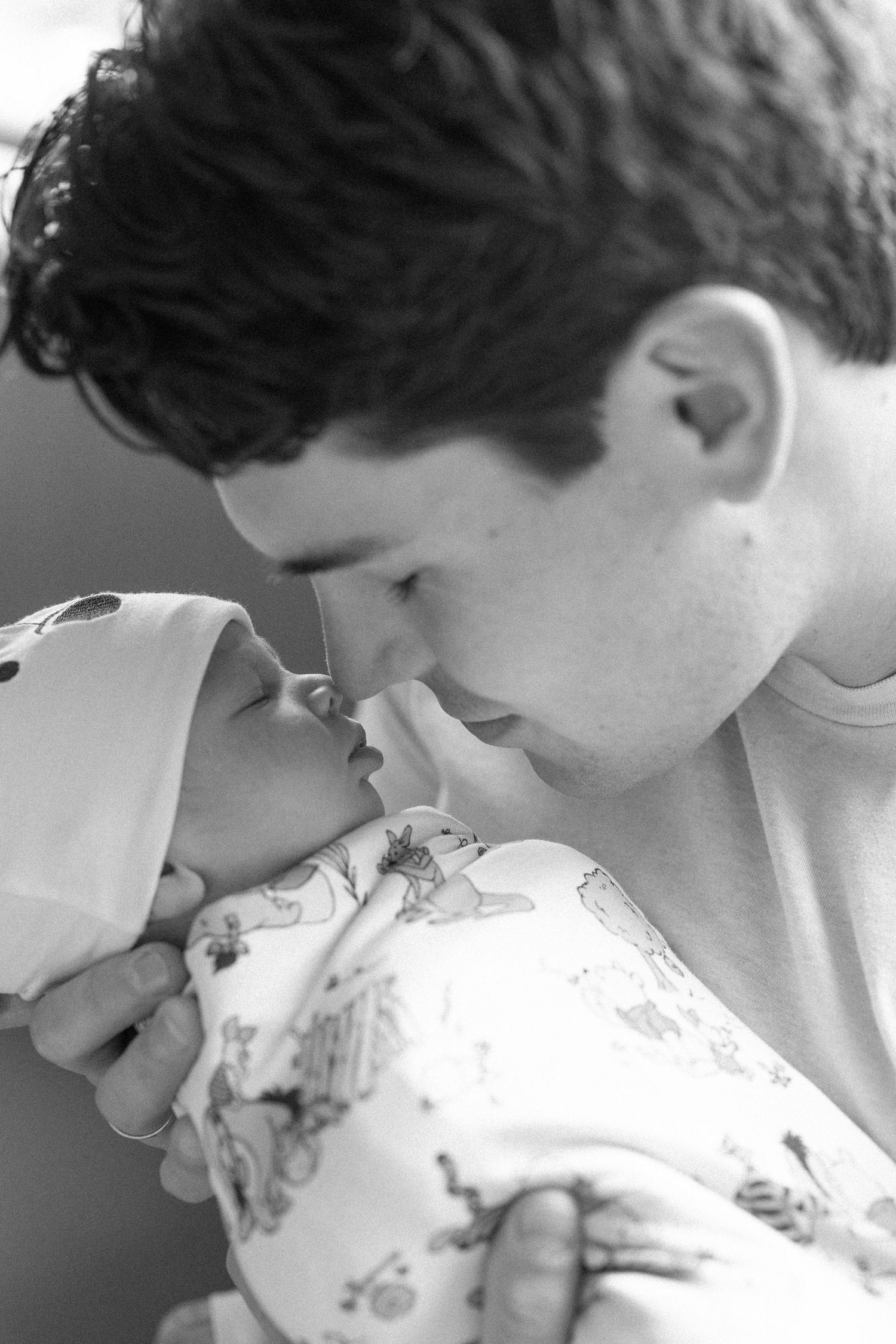 A couple shares an intimate moment while looking at their newborn baby in a hospital bed.
