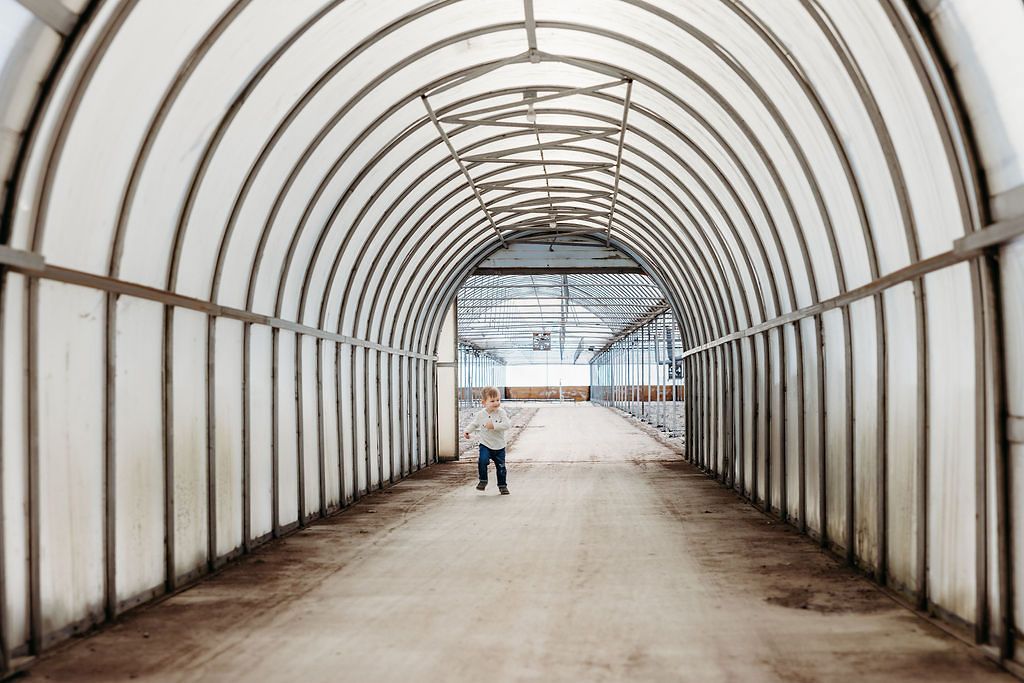 Long covered walkway with curved white ceiling and repeating arch supports extends into the distance.