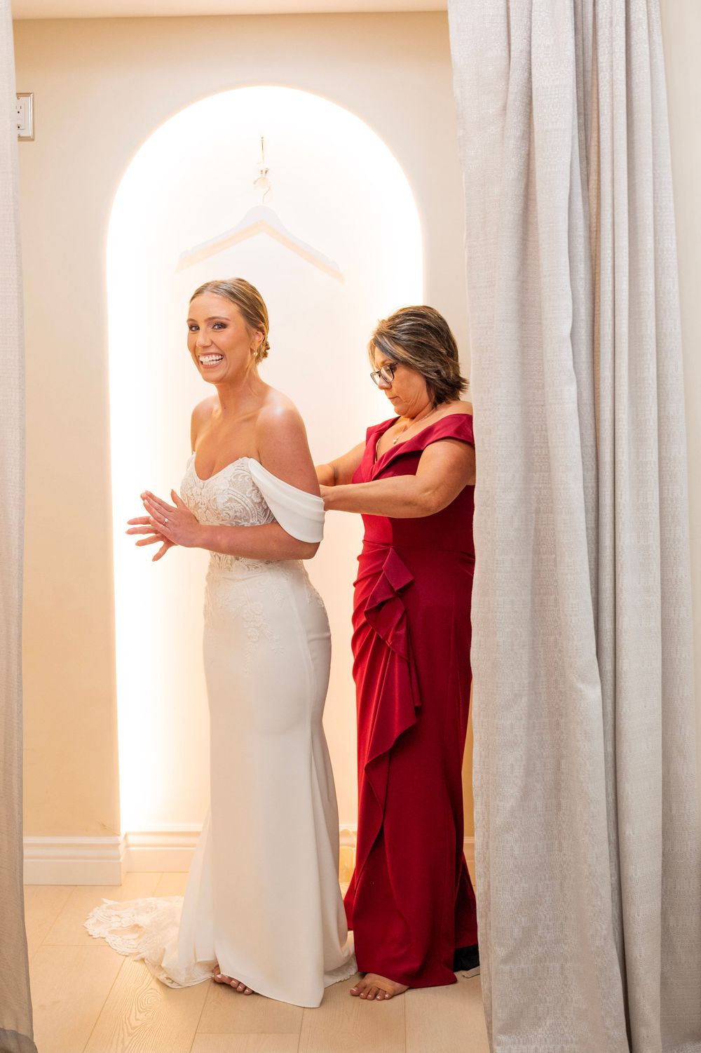 Series of joyful moments captured in a bridal preparation room with white walls and arched doorways.