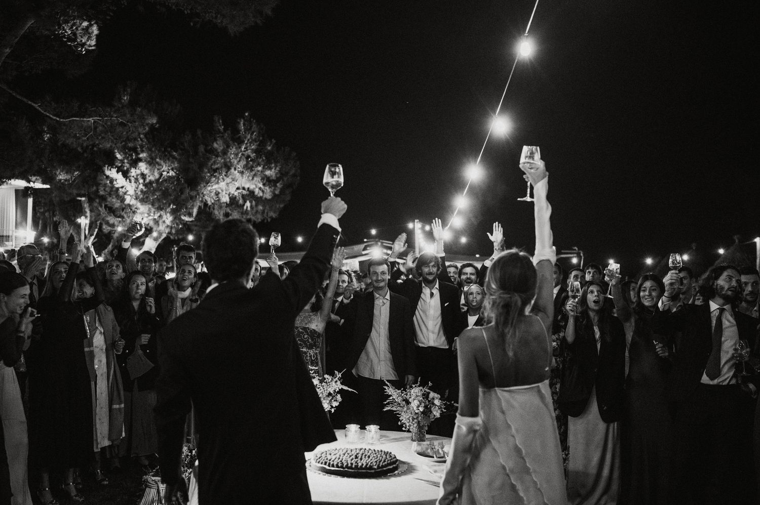 Night wedding reception with string lights illuminating couples dancing.