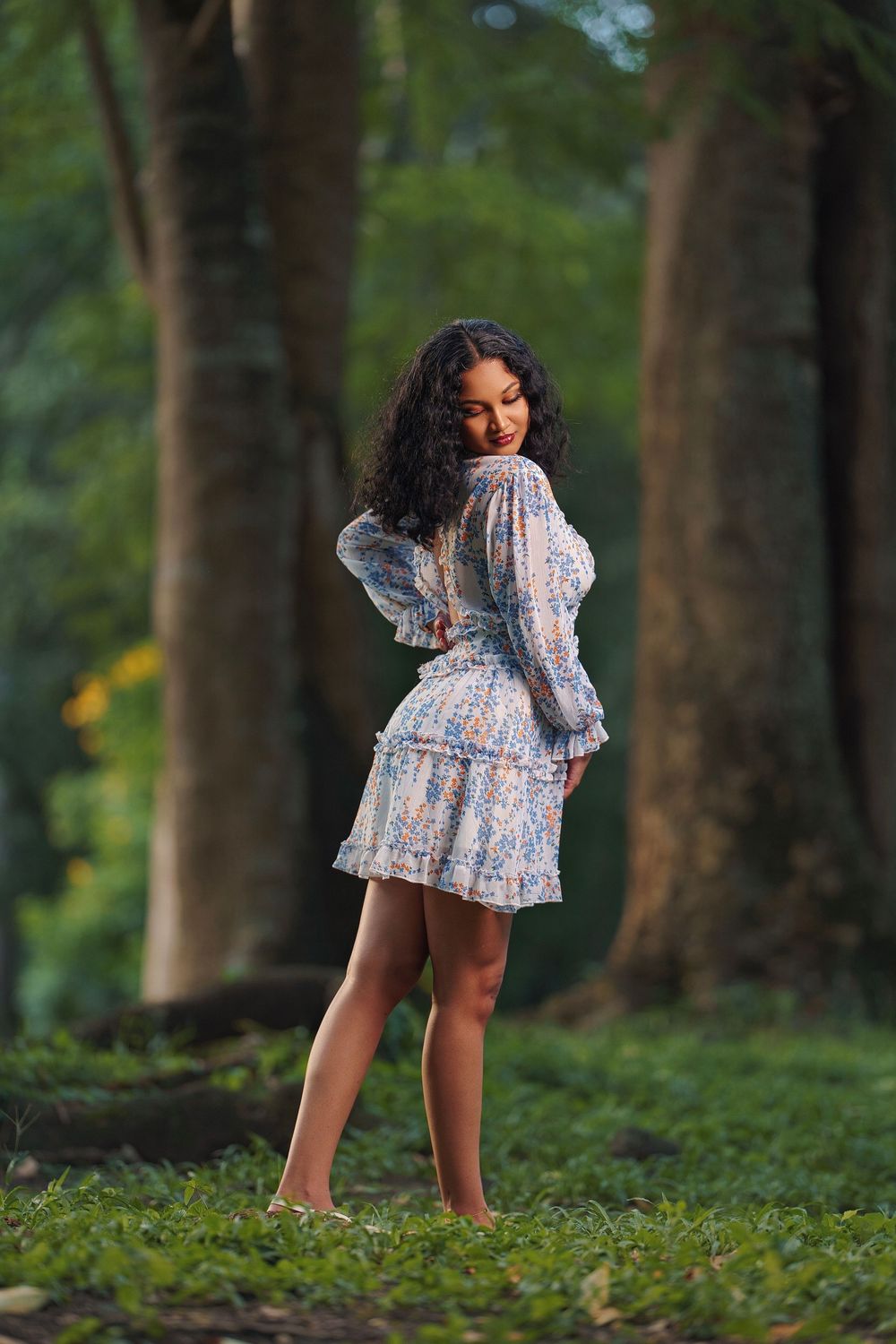 A person in a floral dress poses in a series of artistic shots in a lush green forest setting.