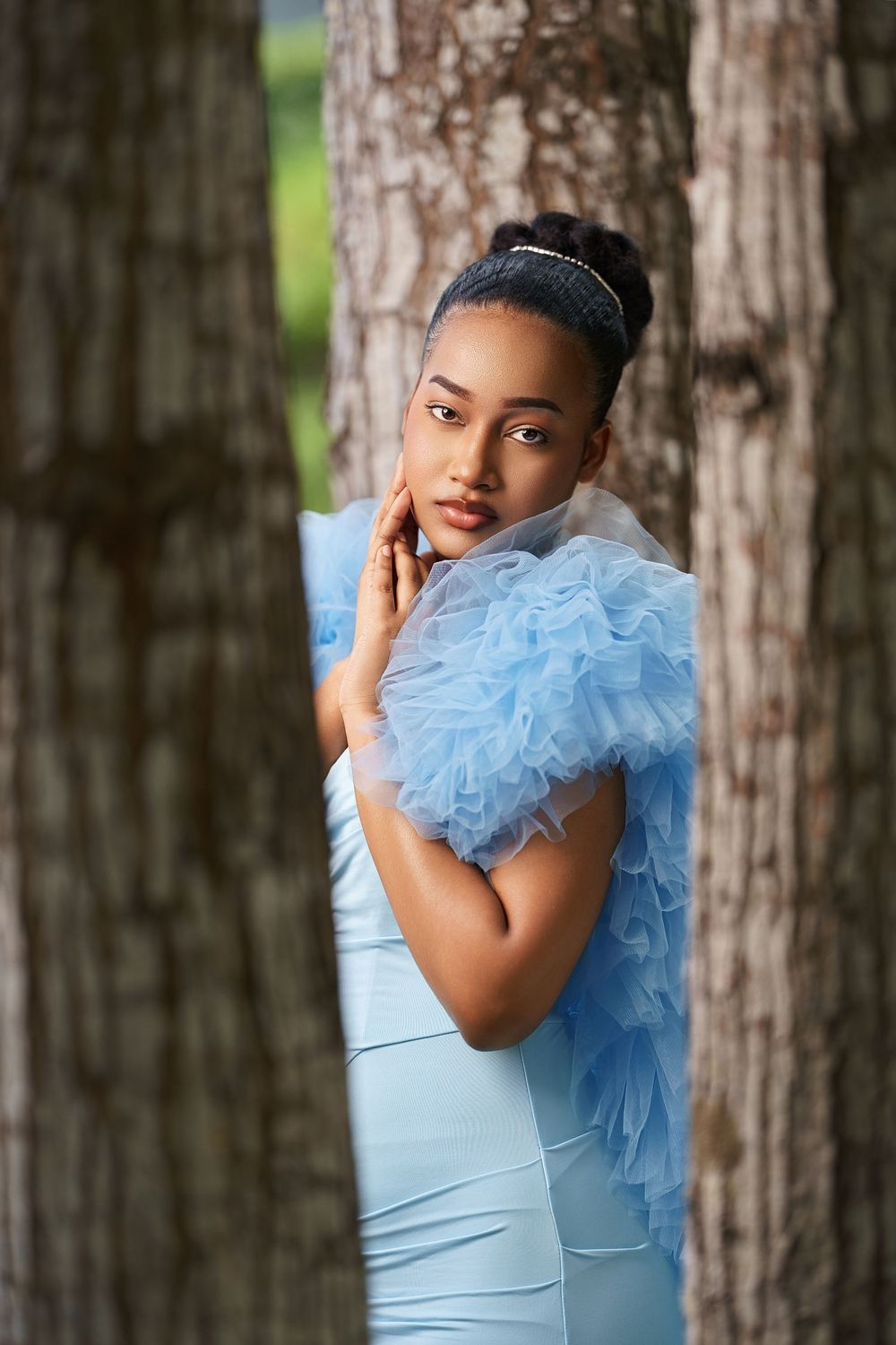 A series of artistic portraits in a light blue dress with a dramatic ruffled accent against a wooded backdrop.