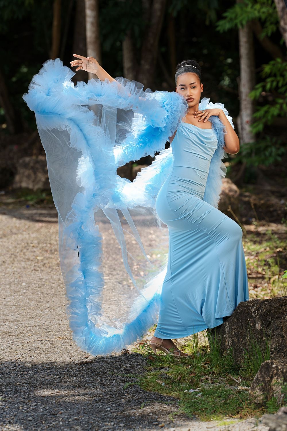 A series of photos showing someone in a light blue dress creating a dramatic effect with blue smoke in an outdoor setting.