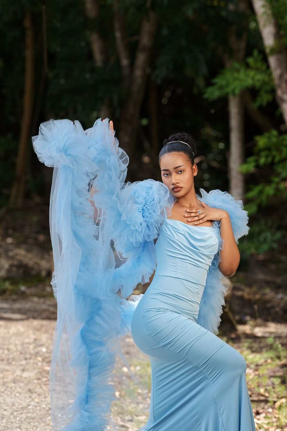 A maternity photo sequence showing a flowing light blue dress with tulle details in a wooded outdoor setting.