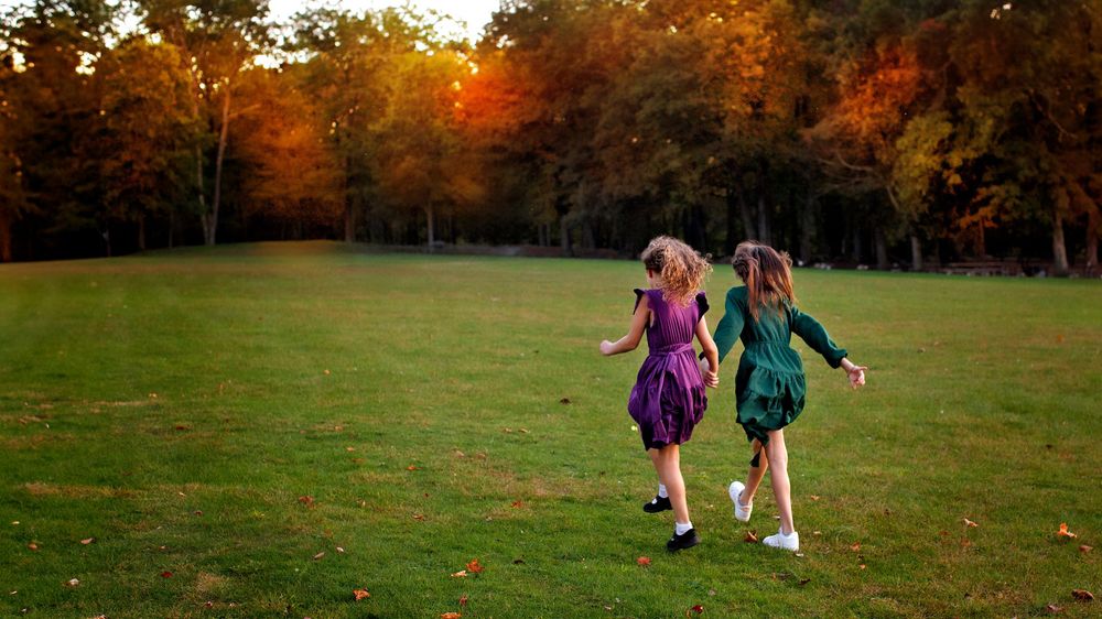family photographer Bergen County NJ outdoor photo session sisters skipping in field