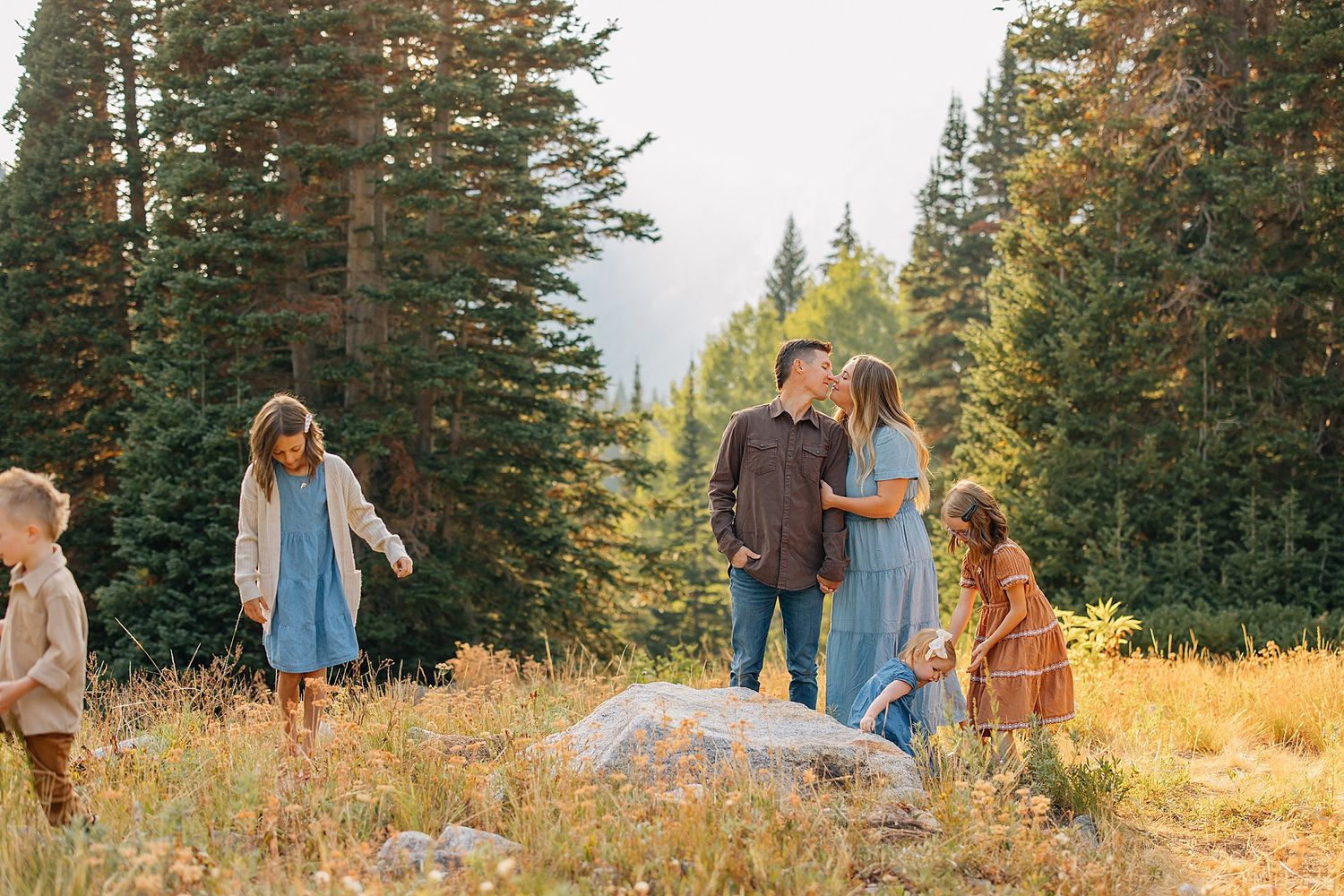 A group enjoys a scenic mountain meadow surrounded by evergreen trees during golden hour in autumn.