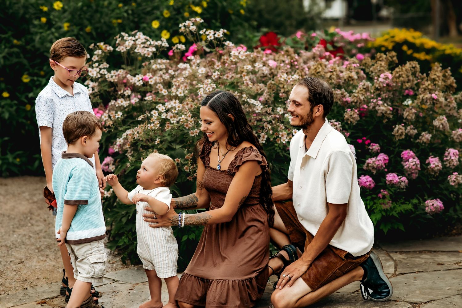 A family shares joyful moments together in a garden filled with blooming pink roses and flowers.