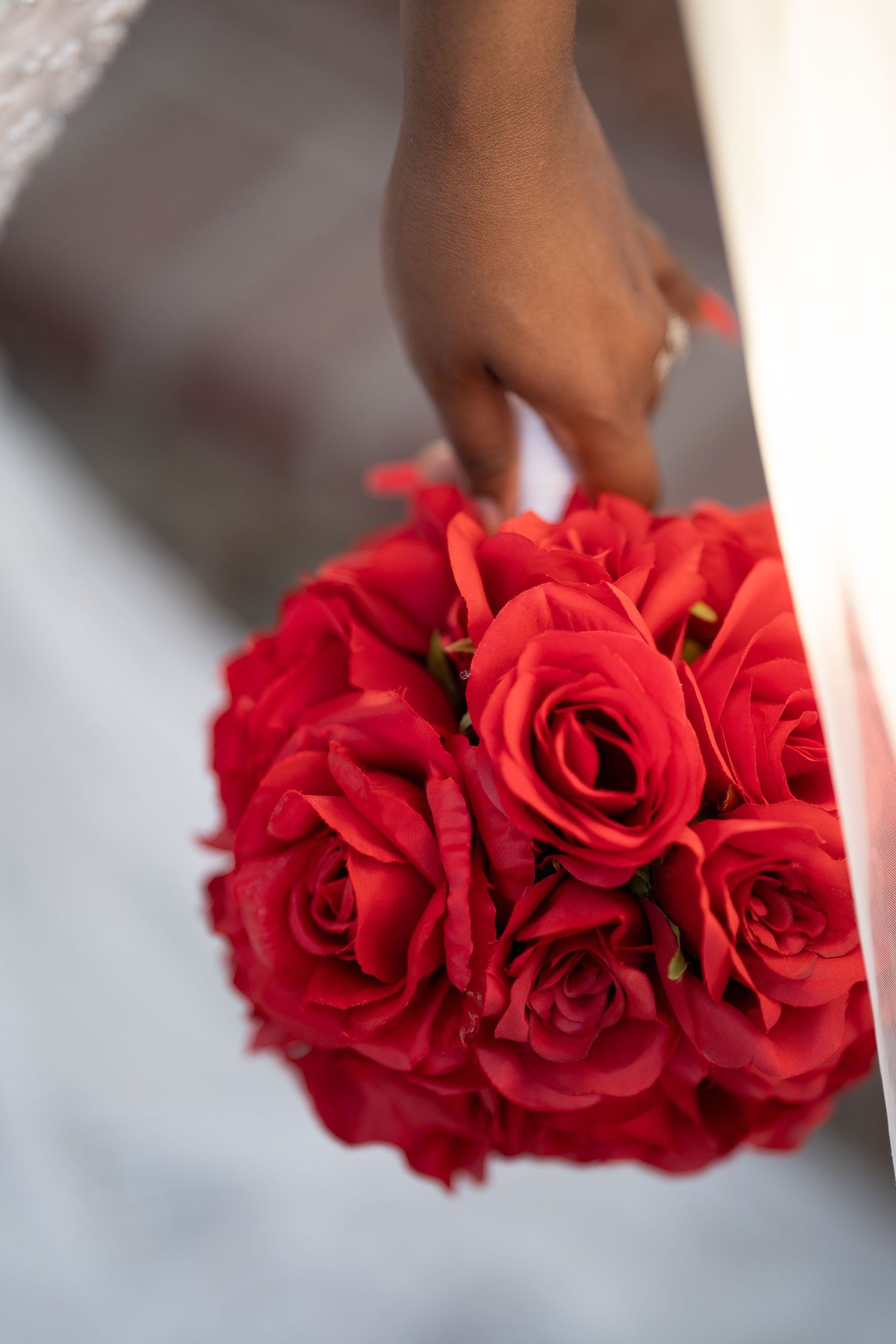 Close-up view of vibrant red roses arranged in a small bouquet against a light background.