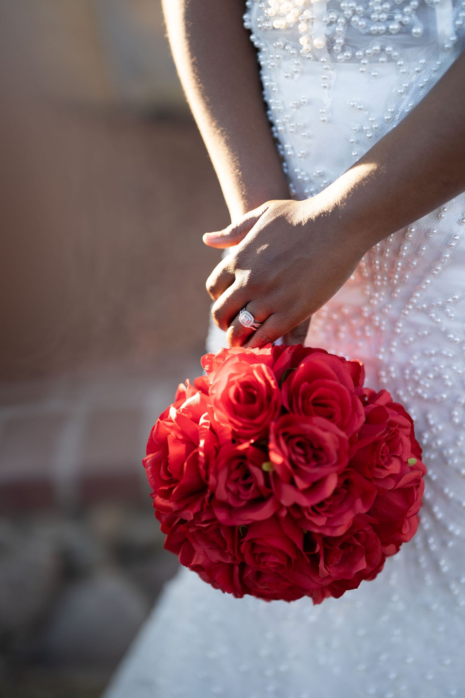 A close-up sequence showing hands holding a vibrant red rose bouquet against a white beaded wedding dress.