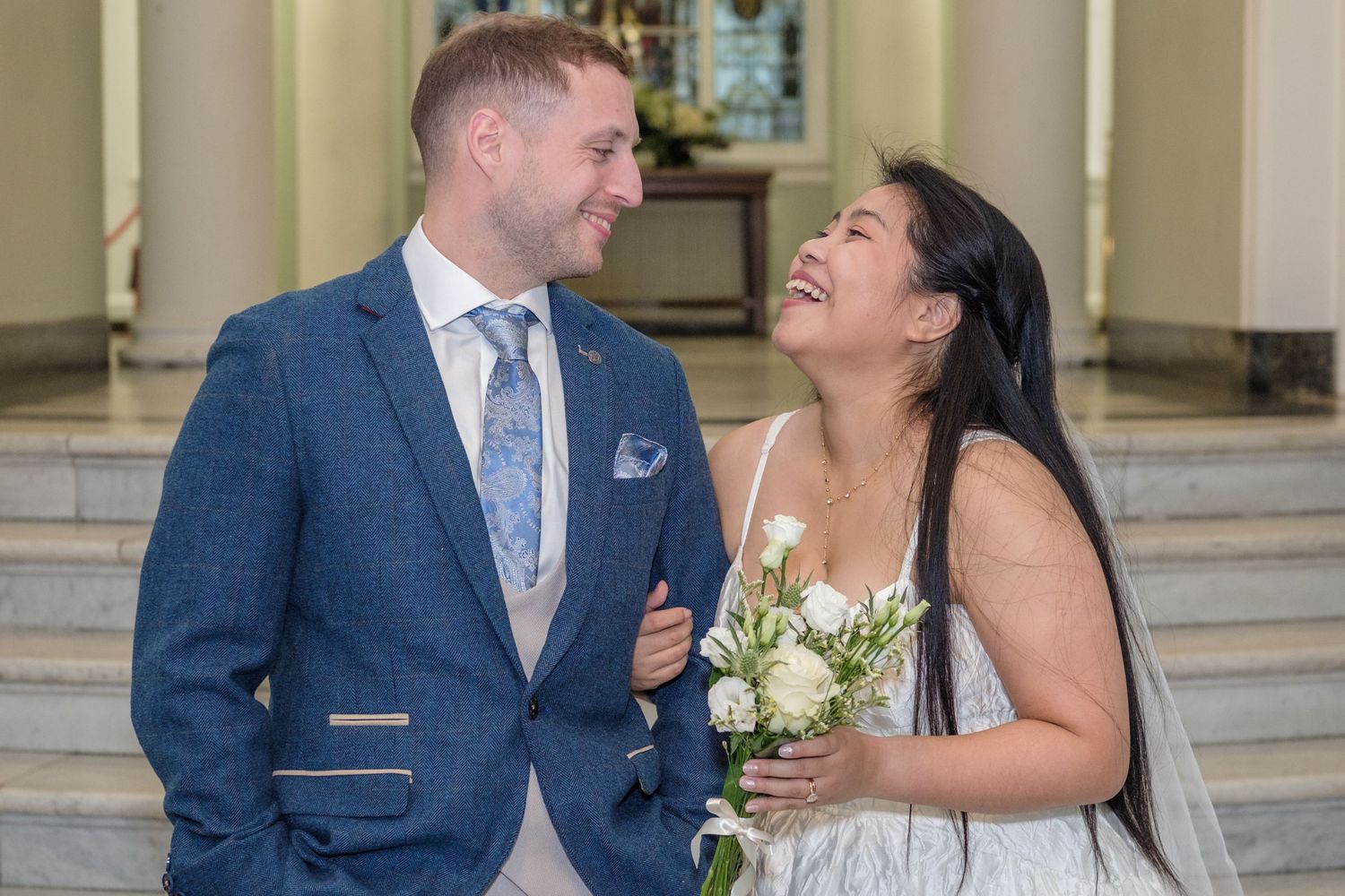 A couple in wedding attire shares joyful moments together while posing for photos on their special day.