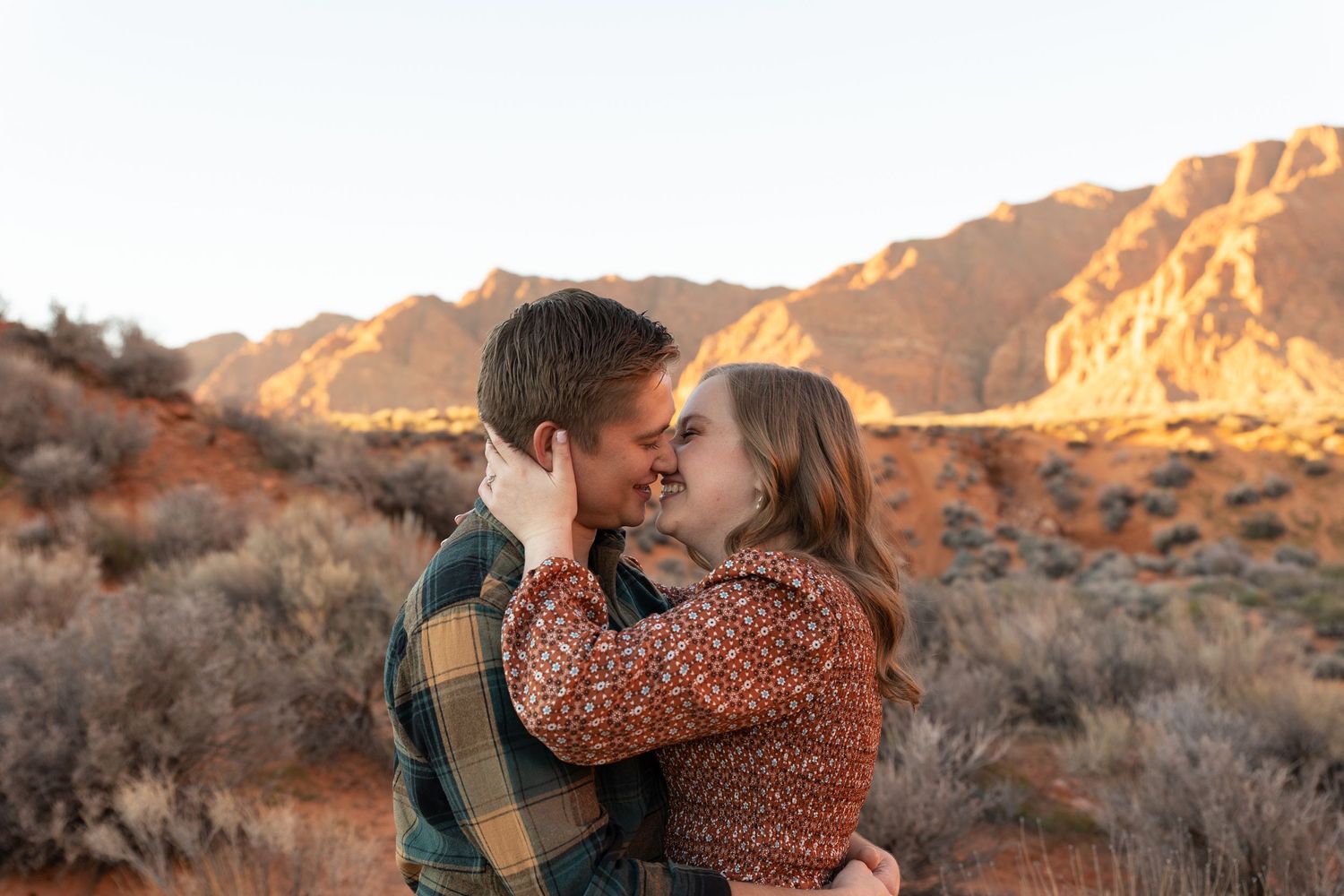man and woman laughing almost in a kiss red mountain in the background