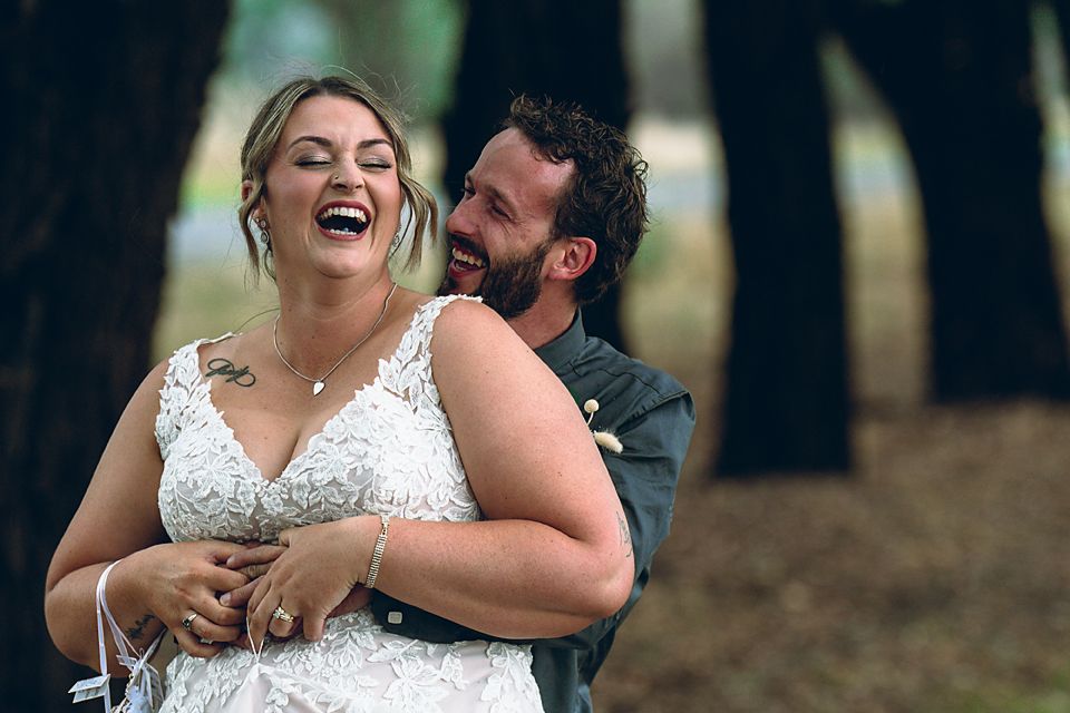Joyful couple laughing and embracing in a romantic outdoor wedding photo session.