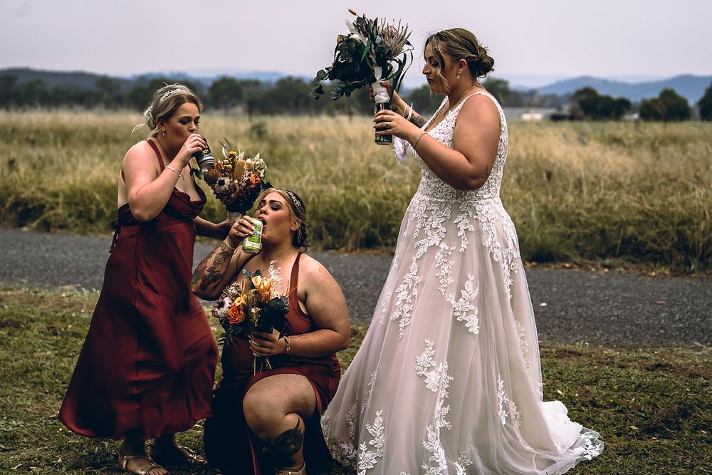 A couple shares a celebratory drink together outdoors during their wedding photoshoot.