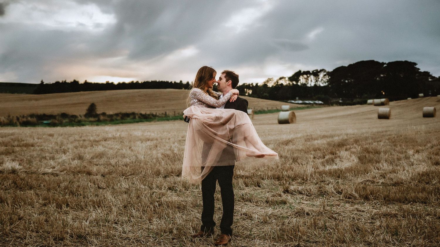 Man holds woman in a field during a romantic engagement session with saundra mouton photorgraphy.