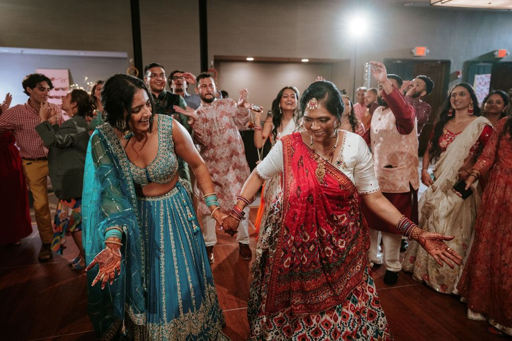 Guests in colorful traditional Indian attire dancing and celebrating at a wedding reception.