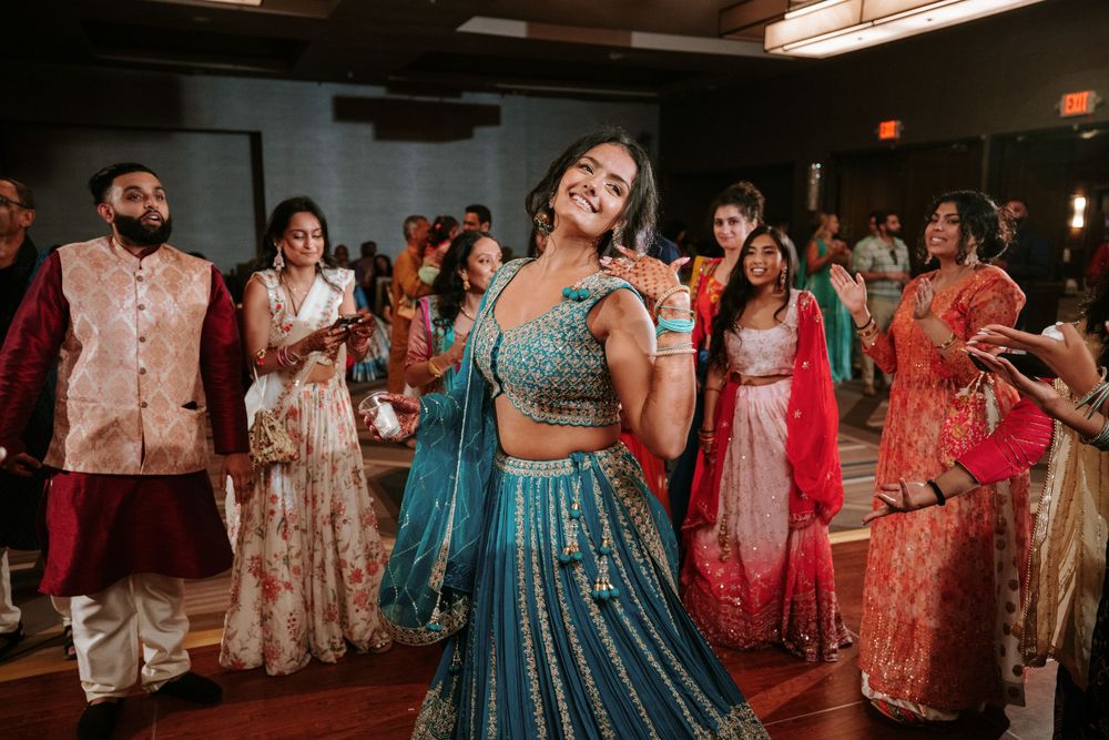 People dancing and celebrating at a vibrant Indian wedding reception with traditional attire and colorful decor.
