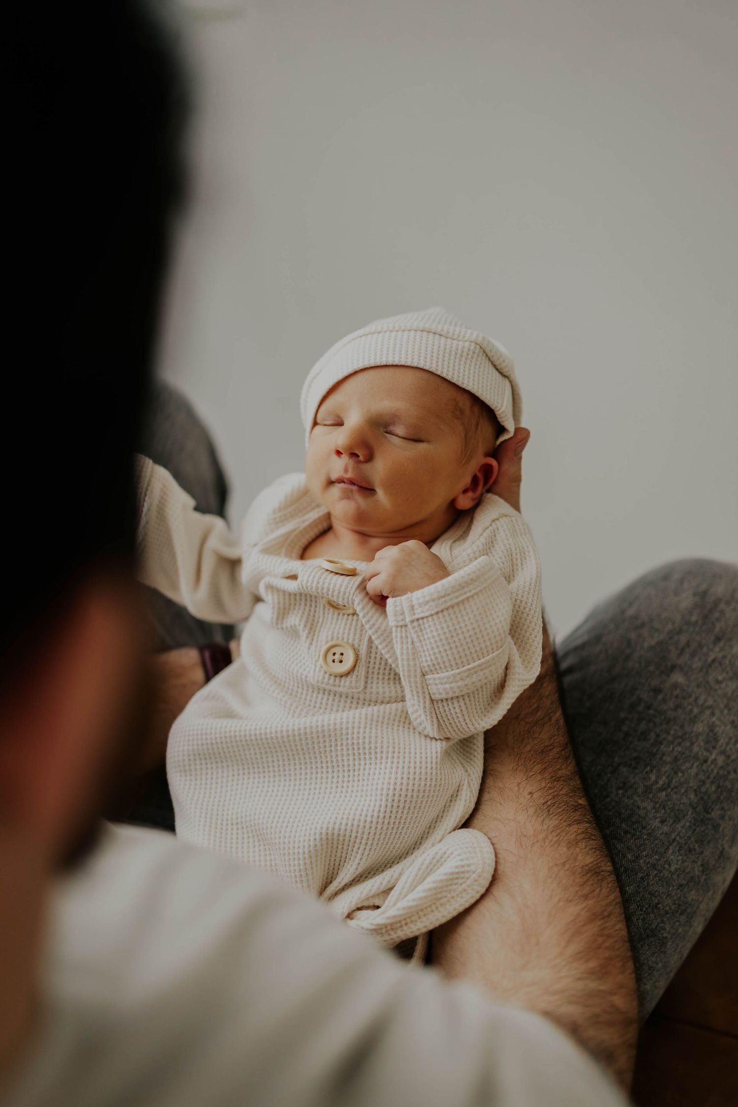 A sleeping newborn baby rests peacefully on a gray blanket in soft lighting during newborn session in Lakeville MN