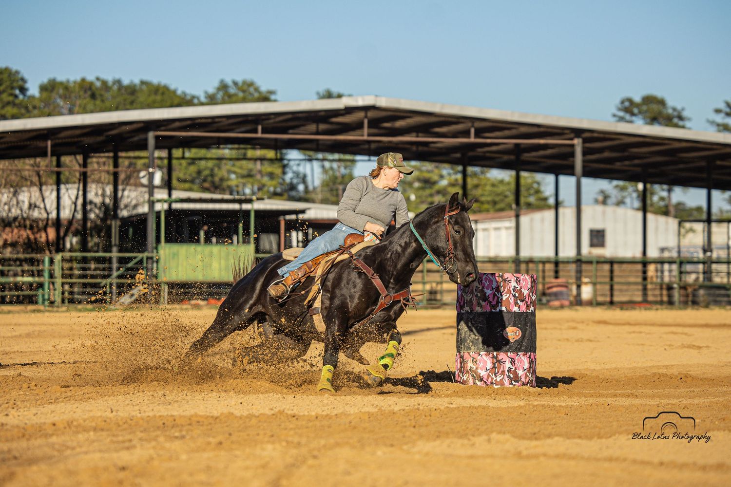A horse arena with covered structures and dirt ground under blue sky.