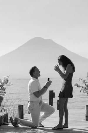 A sequence of black and white photos showing a marriage proposal by the ocean at sunset.
