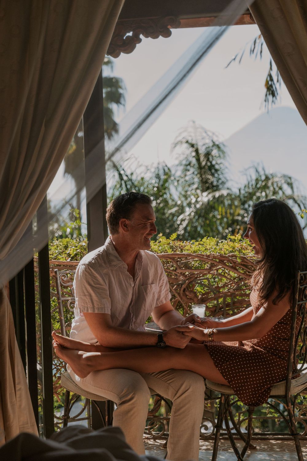 Couple sitting on outdoor patio furniture having an intimate conversation in warm afternoon sunlight.