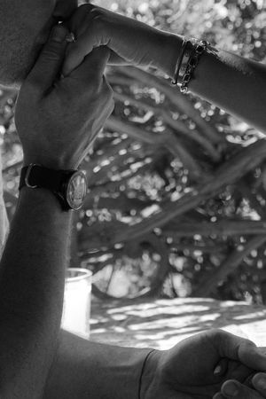 Black and white close-up of metal pipes and joints creating geometric patterns under dappled lighting.