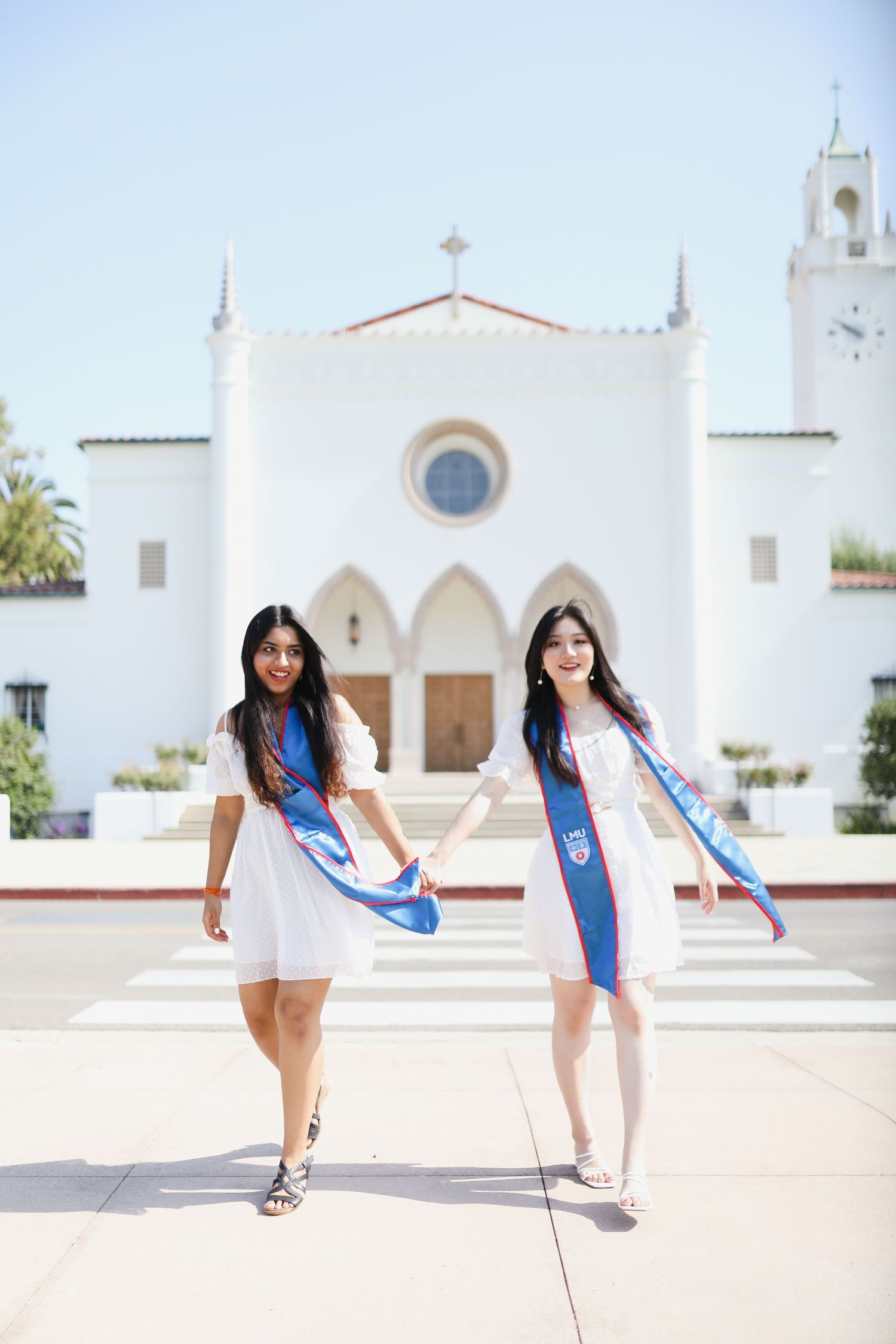 Two friends hold hands and pose for their group graduation photos. Taken by a Bay Area Graduation Photographer.
