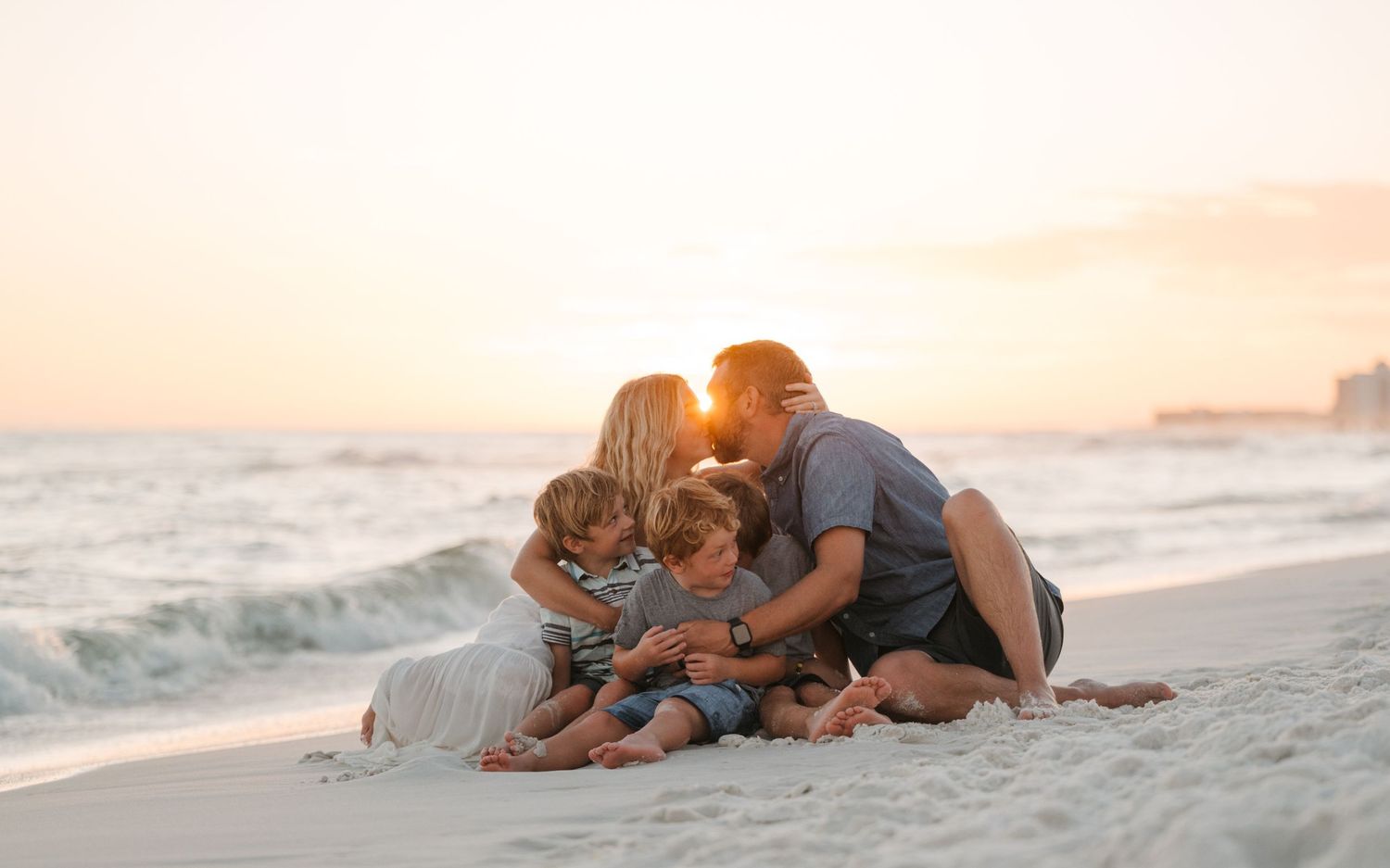 A couple embraces on a sandy beach during a romantic sunset photoshoot.
