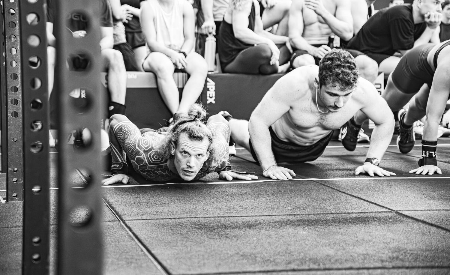 Group of athletes performing push-ups in synchronization during an intense CrossFit workout session.
