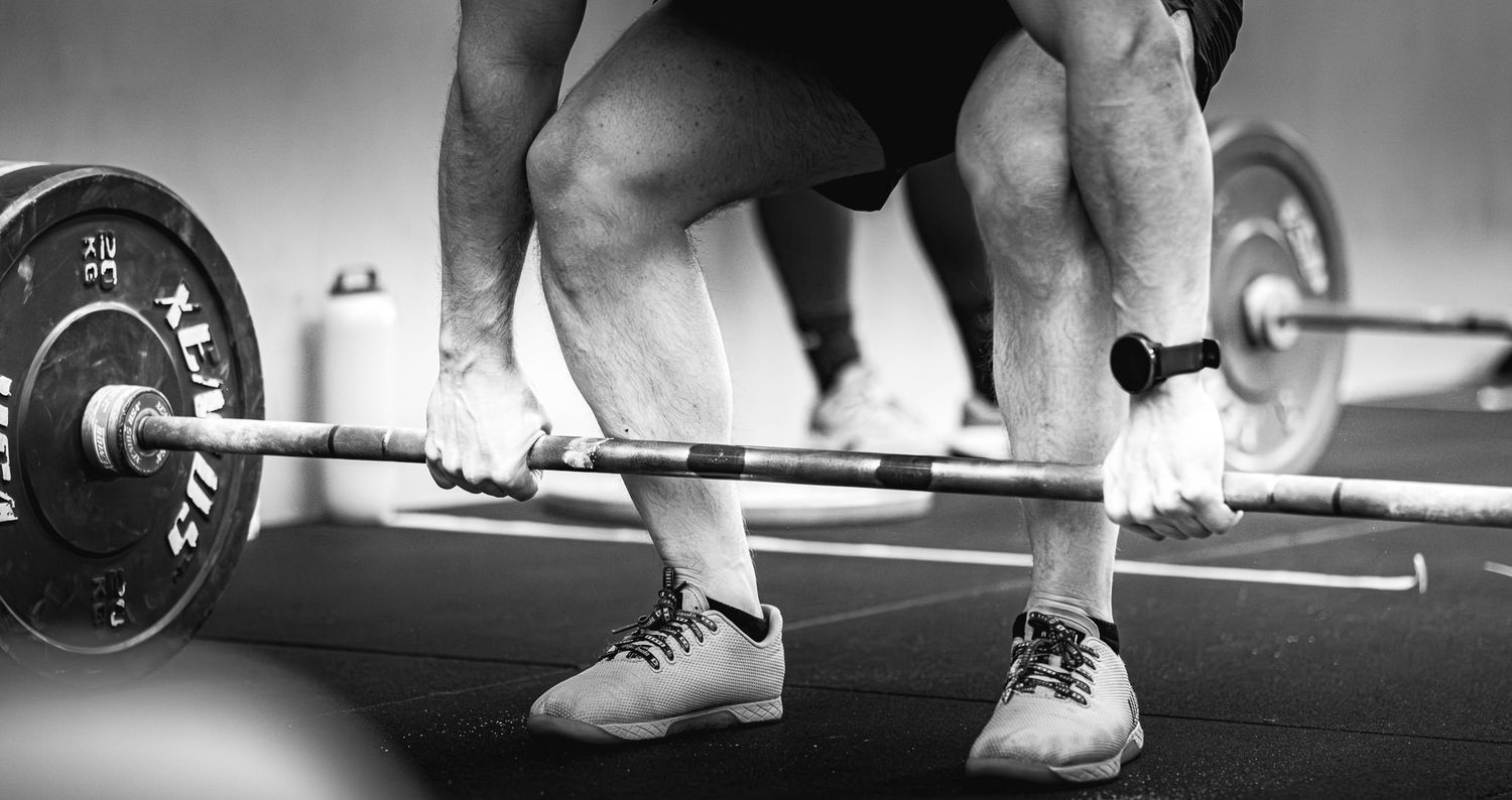 Close-up view of weightlifting shoes and barbells during a training session.