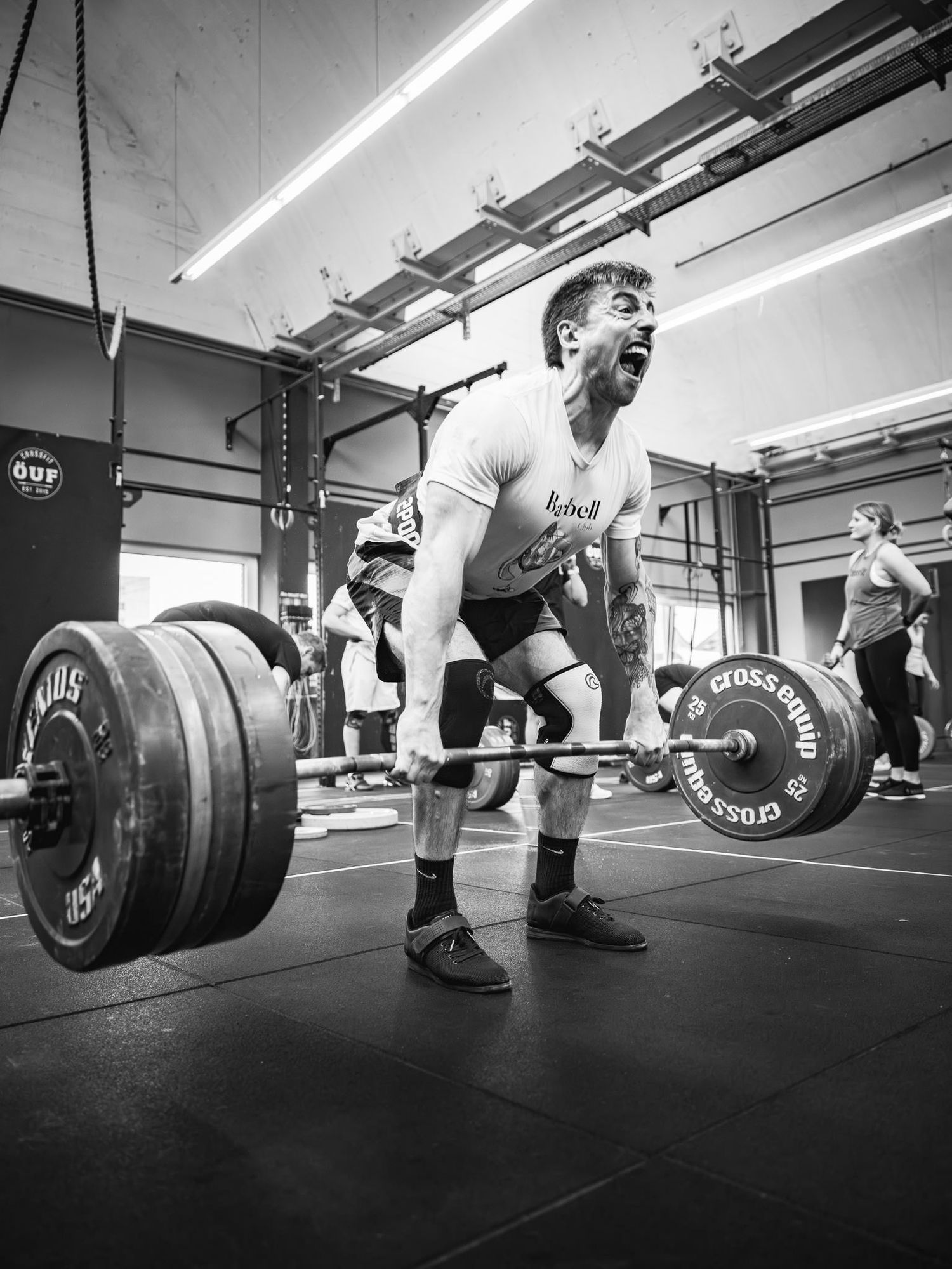 Black and white photo of weightlifters performing deadlifts with heavy barbells.