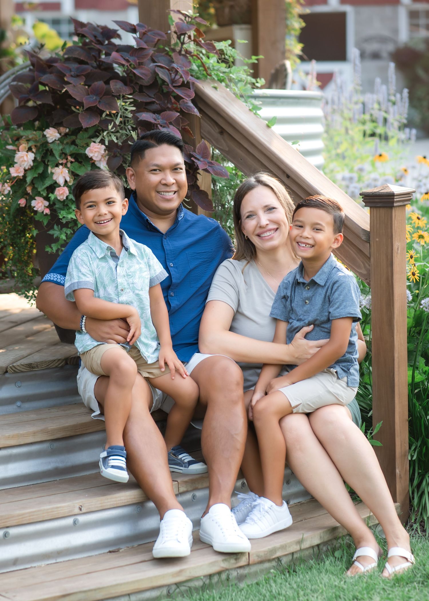 A family sits together on wooden porch steps in coordinated blue and white outfits on a sunny day.