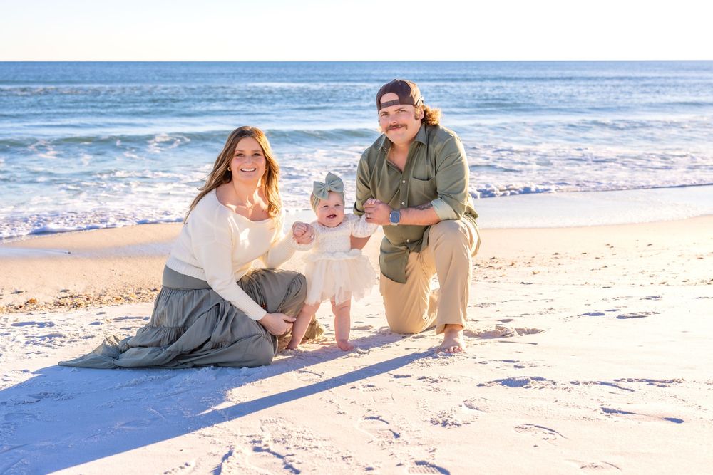 Happy couple lounging and playing on a sunny beach with a blanket and drinks.