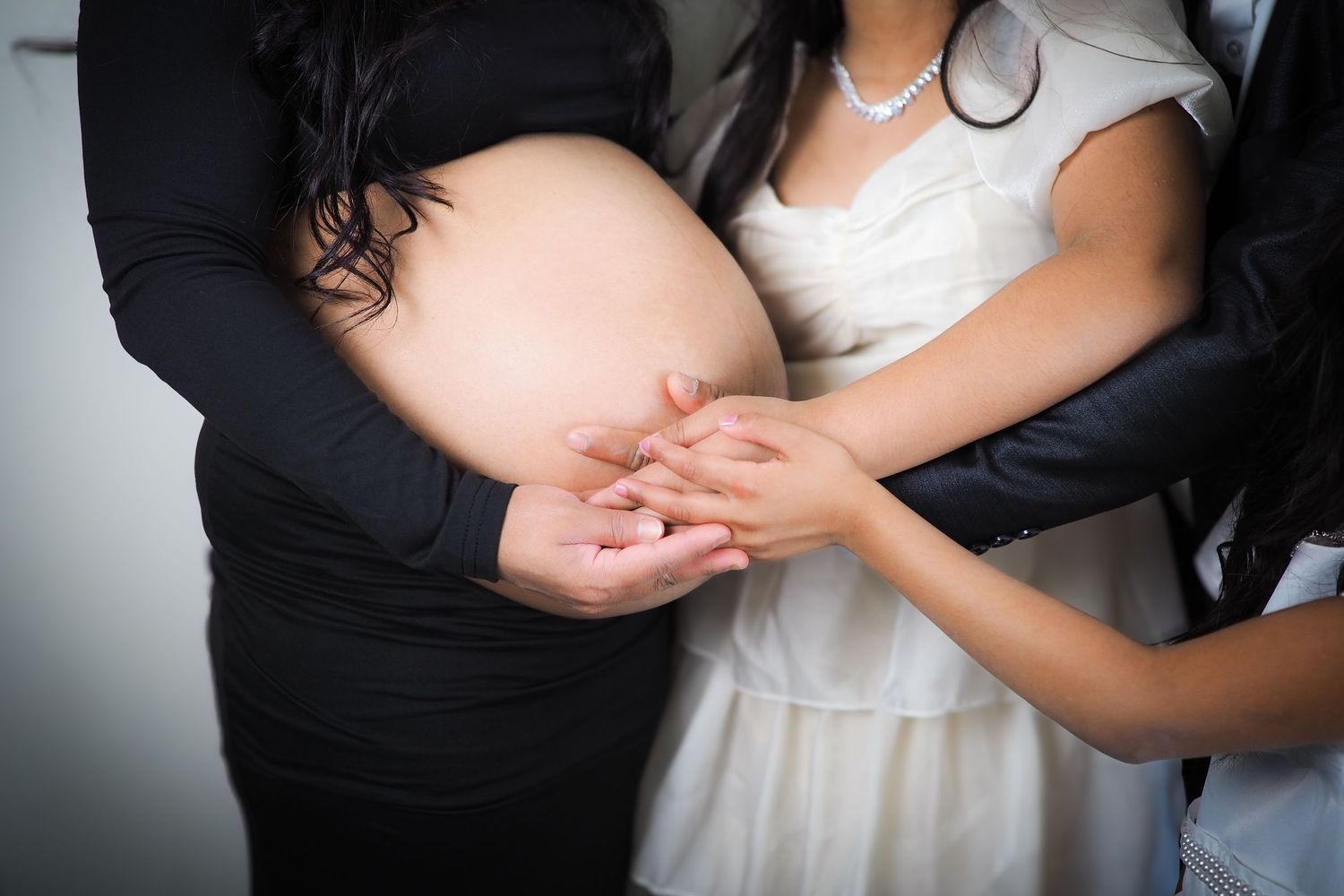 Close-up of hands touching pregnant belly in intimate maternity portrait.