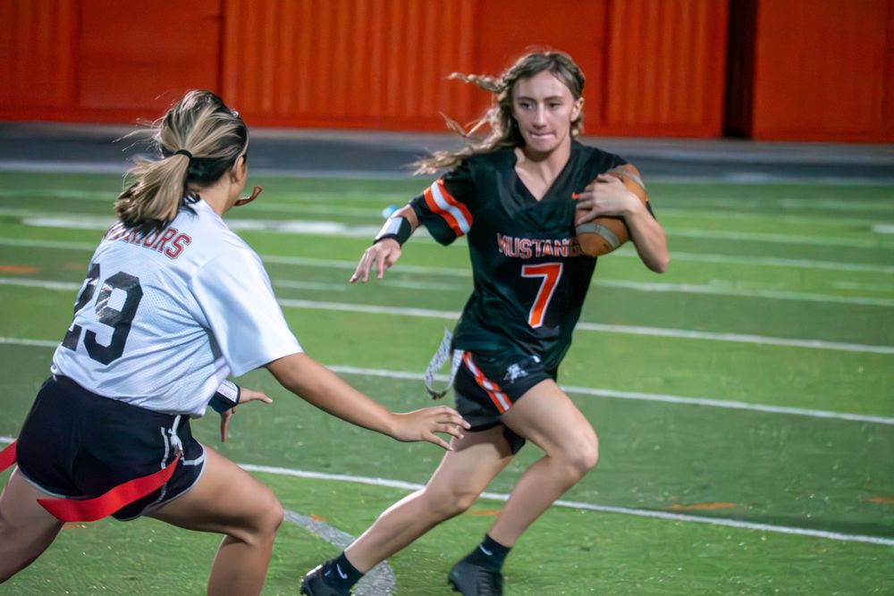 Soccer players compete for the ball during an intense match on an artificial turf field.