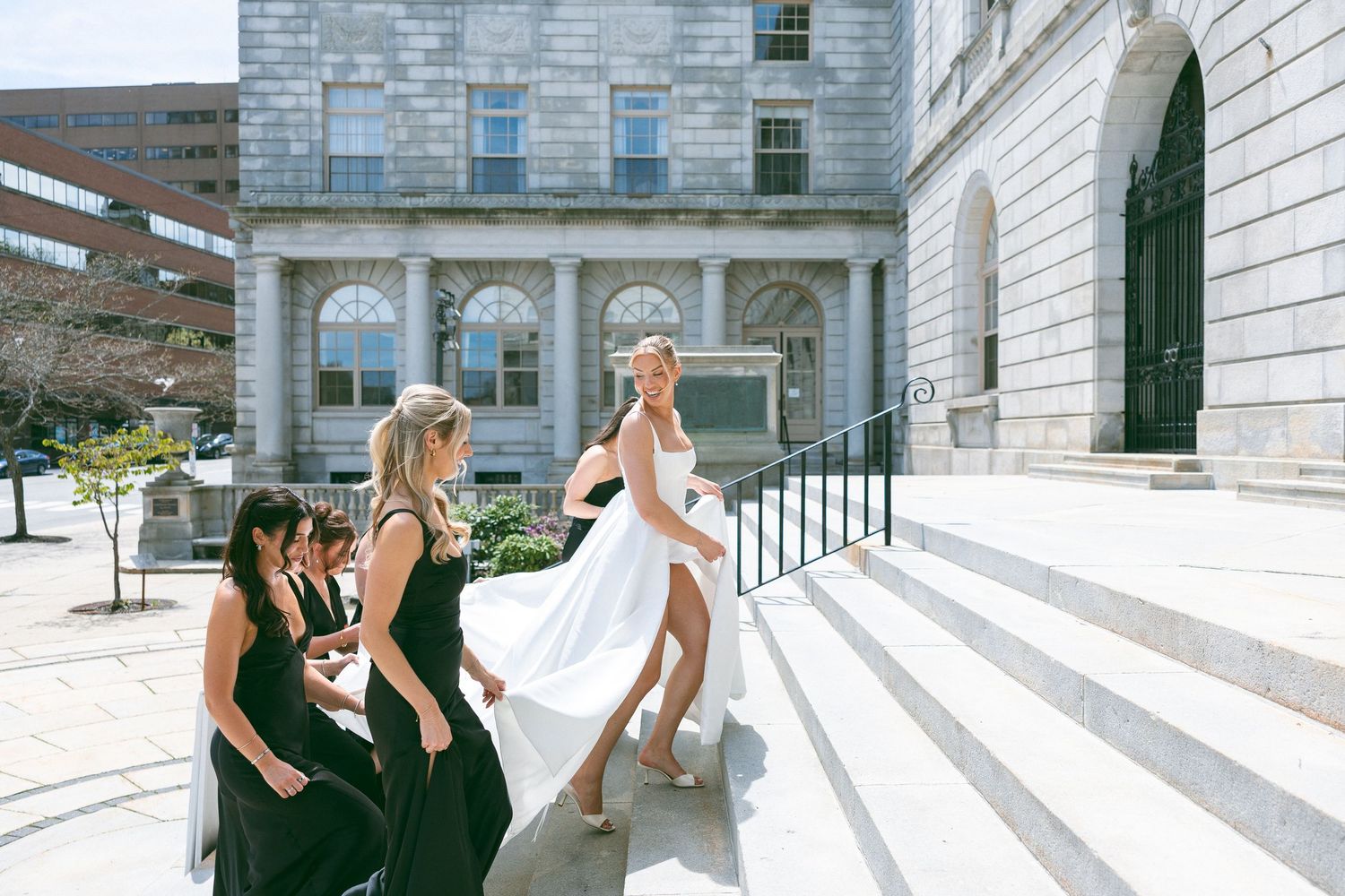 Outdoor wedding celebration with guests gathered on a sunny lawn near trees.