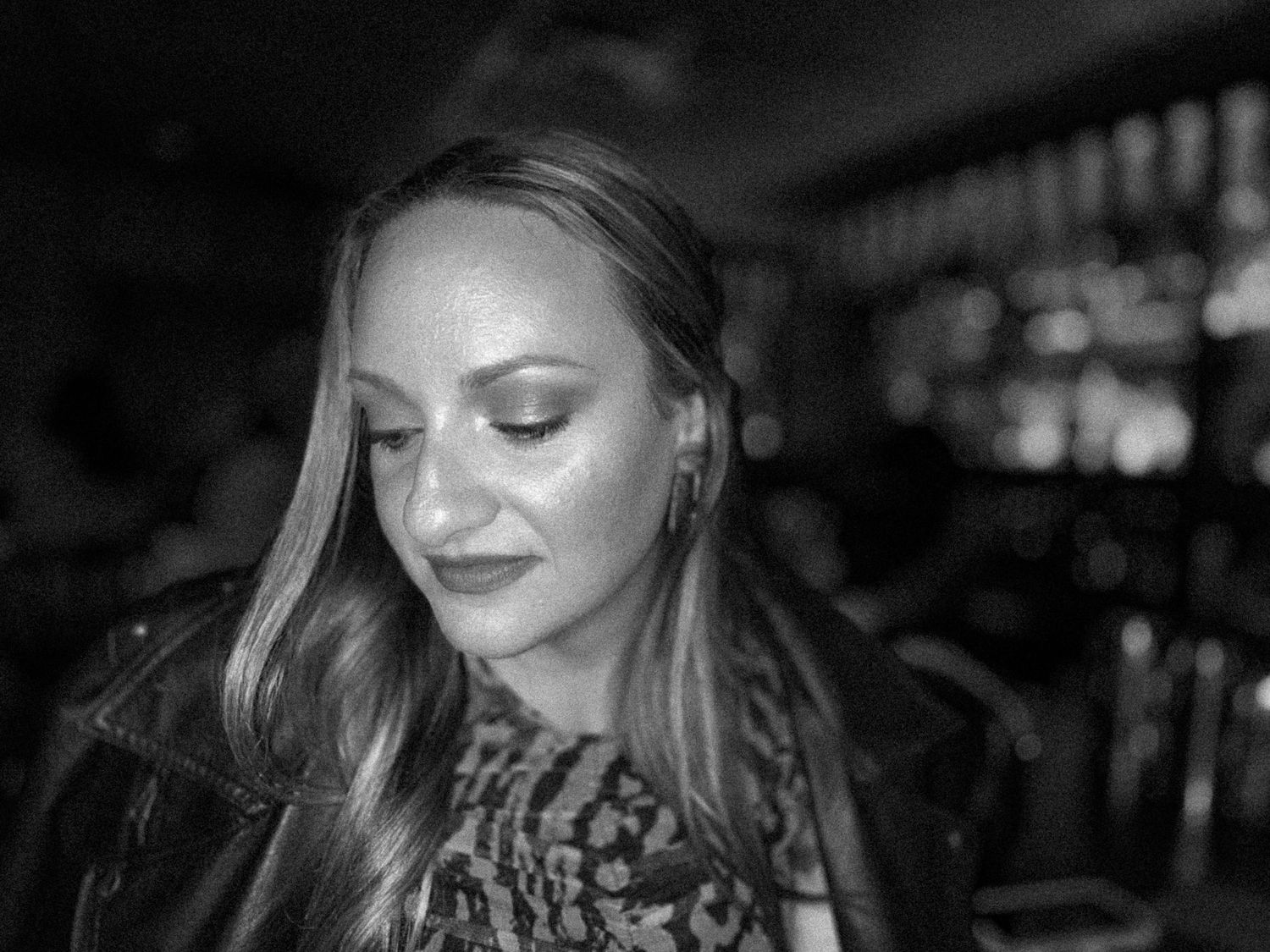 A moody black and white portrait captured in low light at a bar setting.