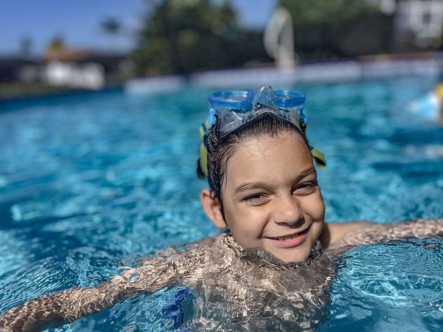 A swimmer enjoying a refreshing dip in a bright blue swimming pool on a sunny day.