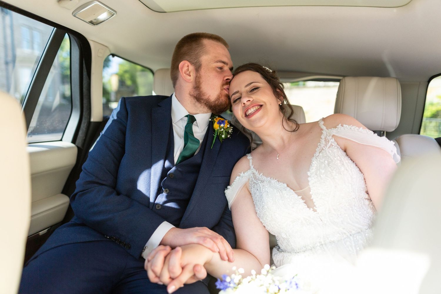 Intimate moment shared in back of luxury car with formal attire.