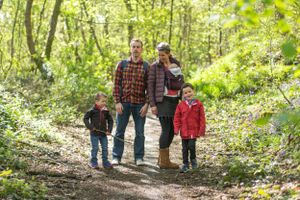 Family walking together on wooded trail during autumn day.