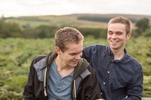 Two people sharing a candid laughing moment in outdoor setting.