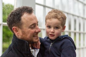 Close up of father and toddler sharing a tender moment against white lattice background.