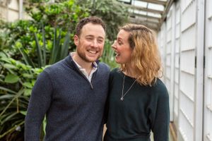 Happy couple laughing together in a greenhouse setting with natural light.