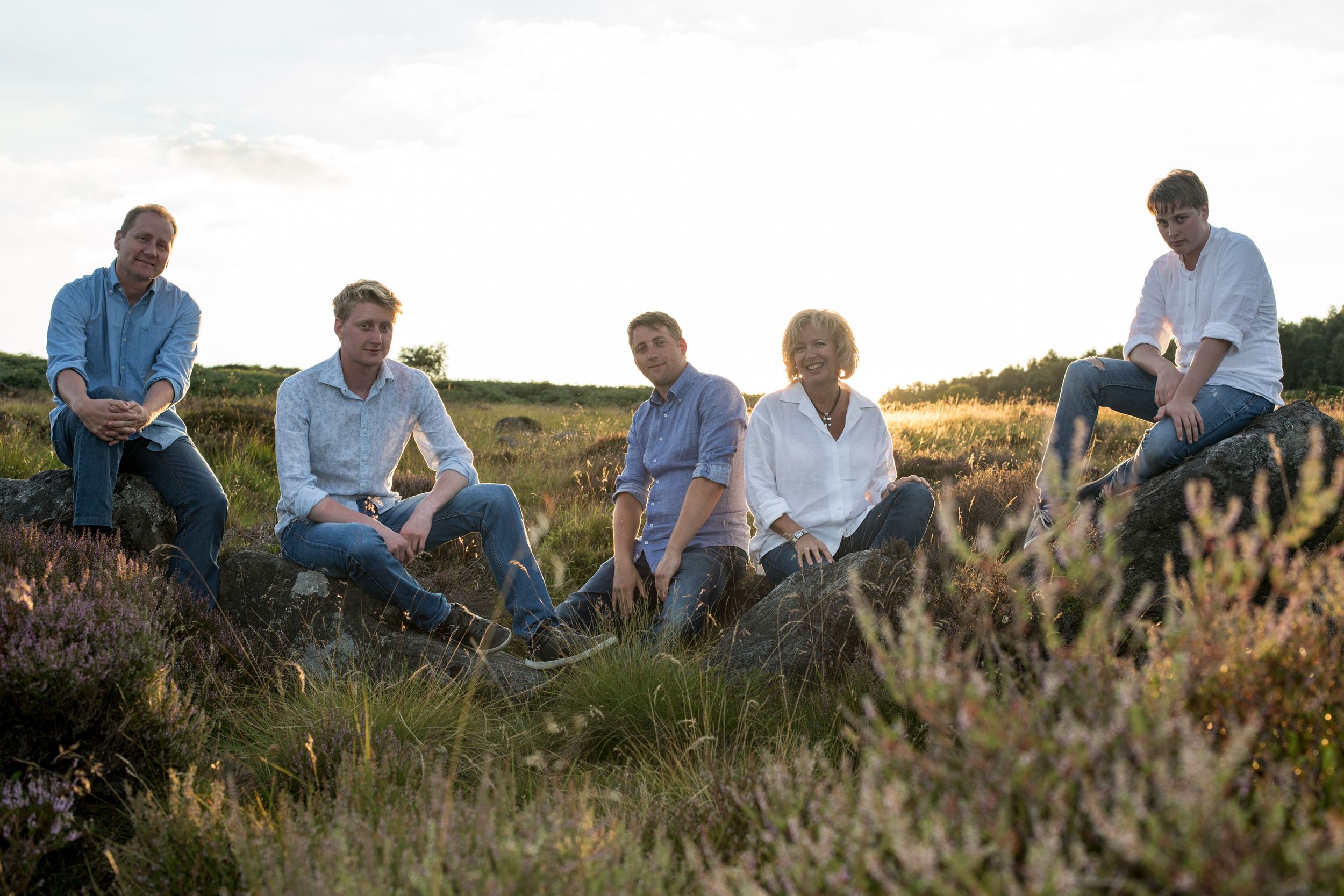 Group relaxing in wild heather on moorland during golden hour.