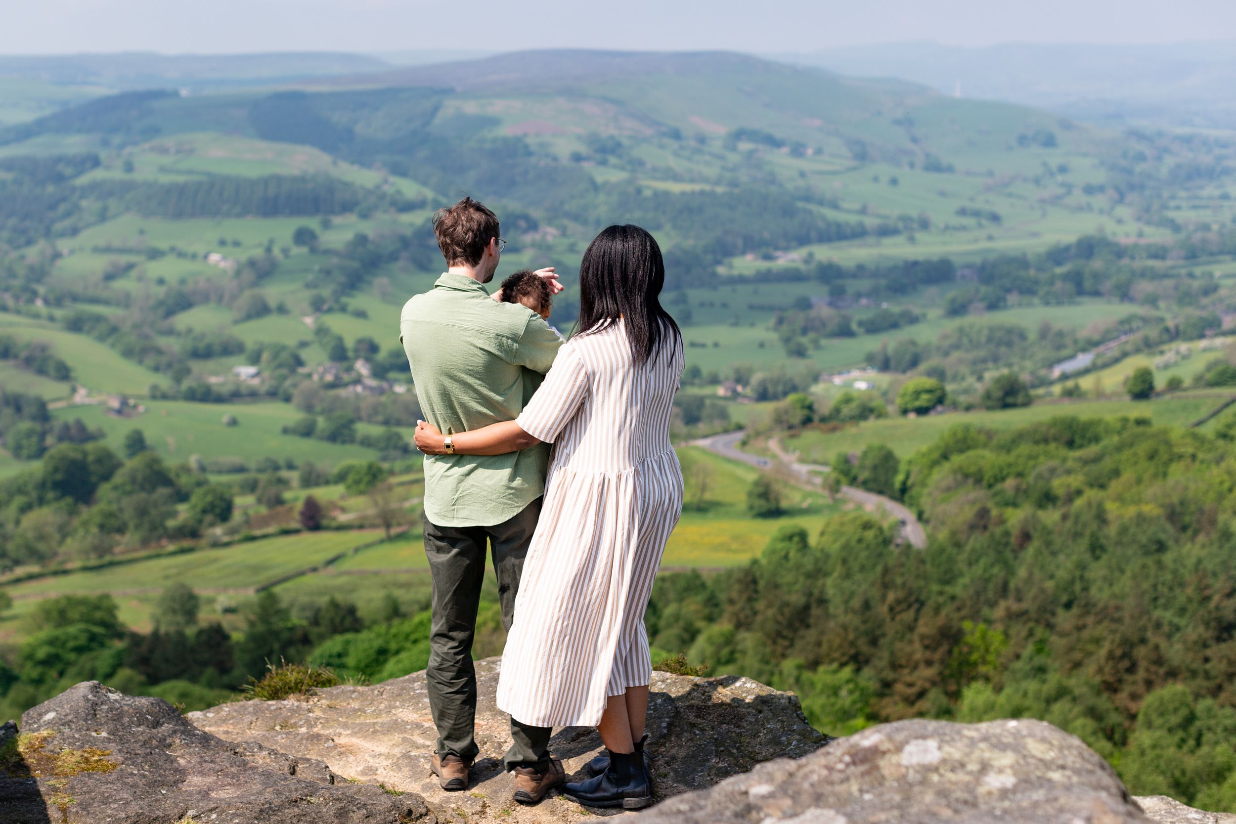 Couple overlooking scenic rolling hills while standing on rocky overlook.